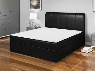 A bedroom scene with a black boxspring bed, a nightstand with a lamp, and a wardrobe.