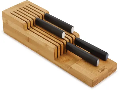A bamboo knife organizer with several knives stored inside, shown on a white background.