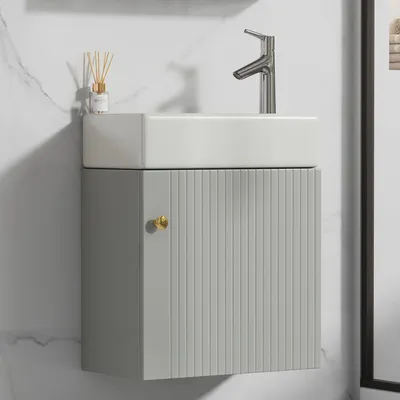 A modern bathroom vanity with a ceramic sink and a single cabinet door.