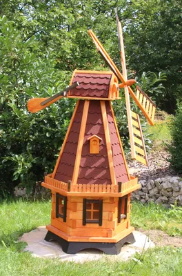 A wooden windmill decoration in a garden setting.