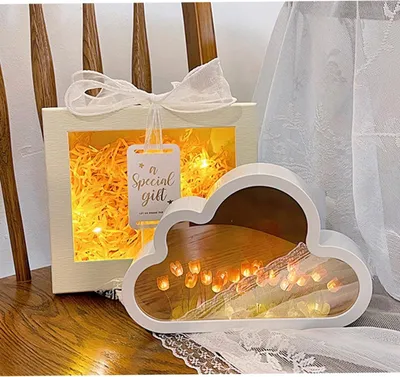 A gift box with lights and a cloud-shaped lamp with lights inside, placed on a wooden surface.