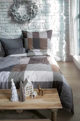 A bed with checkered bedding, decorated for Christmas with a wreath, trees, and a small house.