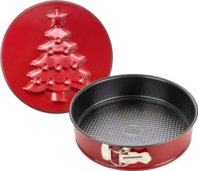 A red springform cake pan with a black interior and a red lid featuring a Christmas tree design.