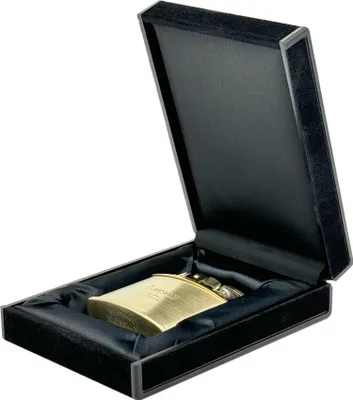 A gold lighter is presented in an open black velvet-lined box.