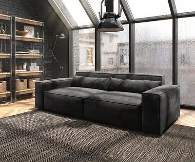 A dark gray sofa is placed in a modern living room with a large window showing a rainy cityscape.