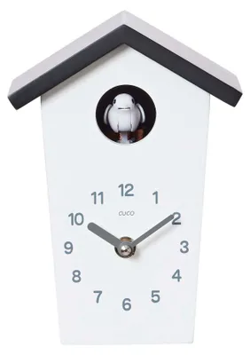 A white cuckoo clock with a black roof and a small bird emerging from a circular opening.