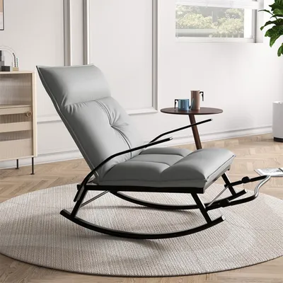 A gray rocking chair is placed on a round rug in a well-lit room.