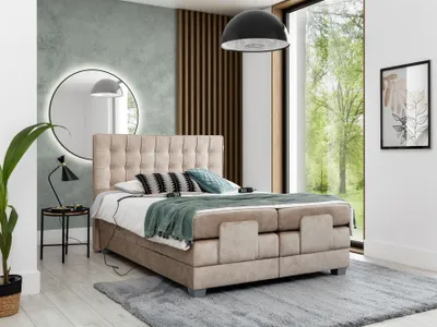 A bedroom scene featuring a beige boxspring bed with a large window overlooking trees.