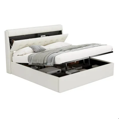 A white upholstered bed frame with the mattress base lifted to reveal storage space underneath.