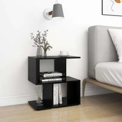 A black bedside table with books and decorative items next to a bed.