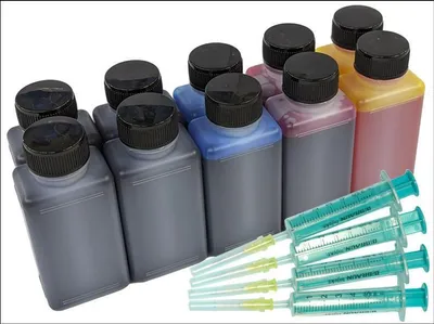 A collection of ink bottles and syringes on a white background.