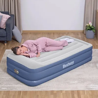 A woman sleeps on an inflatable mattress in a room.
