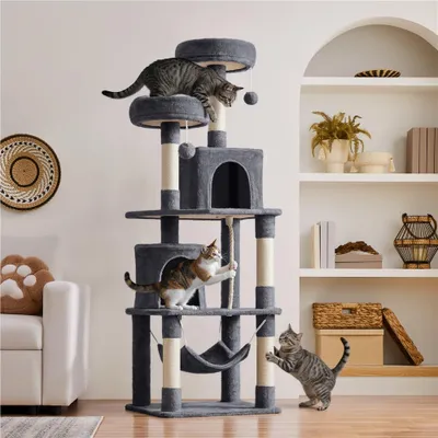 Three cats playing on a multi-level cat tree in a living room setting.