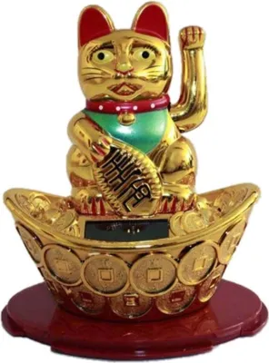 A golden lucky cat figurine sits on a base decorated with coins.