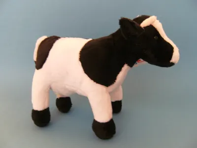 A plush toy cow on a plain blue background.