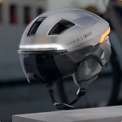 Produktbild von ABUS Fahrradhelm HYP-E ACE - mit Frontlicht, Rücklicht und Blinklicht - mit Visier und Ohrenschützern - geeignet auch für E-Bike und S-Pedelec - für Damen und Herren - Silber, Größe L (57-61 cm)