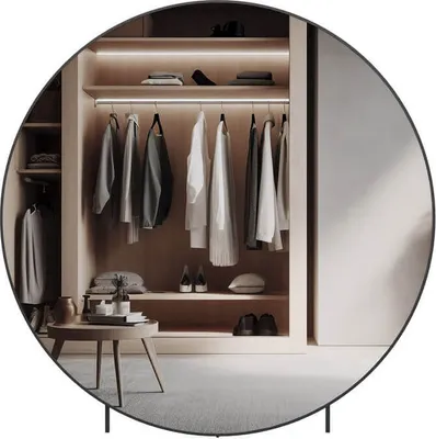 A circular mirror reflects a modern, well-organized closet with clothes neatly hung and shelves displaying accessories.