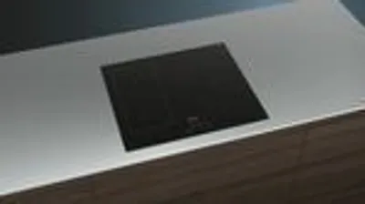 A close-up, angled view of a black induction cooktop embedded in a light gray countertop.