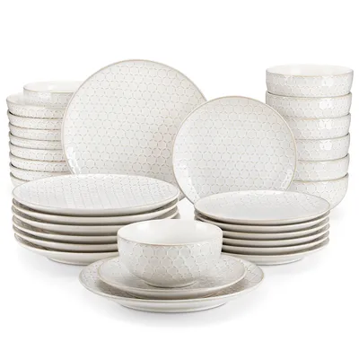 A collection of white ceramic plates and bowls with a subtle geometric pattern, neatly stacked against a white background.