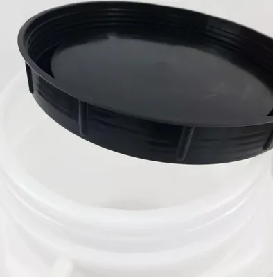 A close-up view of a black lid resting on the rim of a white container.
