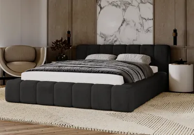 A modern bedroom scene featuring a dark upholstered bed with a patterned rug and a decorative chair.