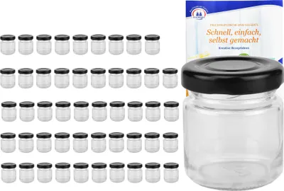 A set of small glass jars with black lids, and a recipe booklet in the background.