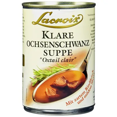 A can of Lacroix Oxtail Soup is shown against a white background, with a spoon scooping some soup and meat from the can.