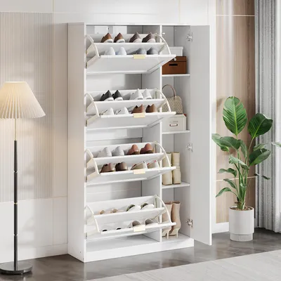 A white shoe cabinet with multiple pull-out shelves filled with shoes, placed in a room with a floor lamp and a potted plant.