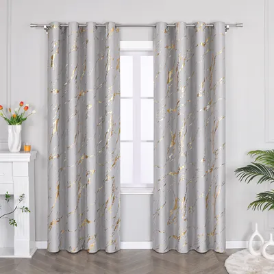 A pair of gray curtains with a gold marble-like pattern hanging in front of a window.