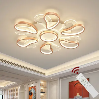 A modern ceiling lamp with petal-like elements, shown in a room setting with a remote control.