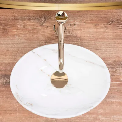 A top-down view of a marble sink with a gold faucet.