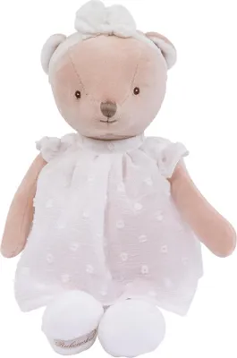 A studio shot of a teddy bear wearing a dress and a headband.