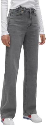 A person wearing jeans and a white long-sleeved shirt, standing and posing.