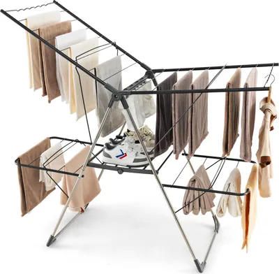 A silver folding drying rack with clothes and shoes on it, set against a white background.