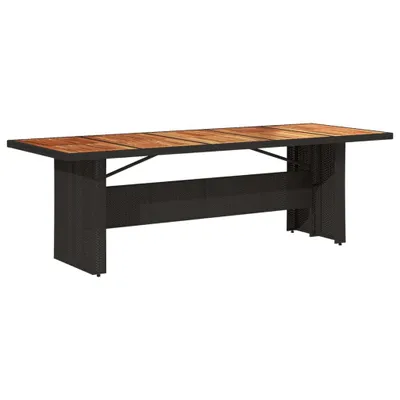 A long, rectangular outdoor dining table with a wooden top and a dark woven base, shown against a white background.