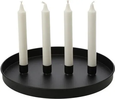 Four white candles with black bases stand upright on a round black tray.
