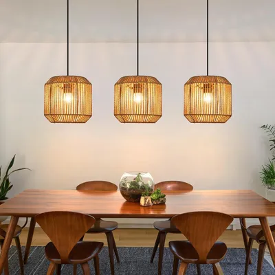 A dining room table with chairs and three pendant lights hanging above.