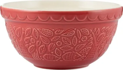A red ceramic mixing bowl with an embossed pattern of leaves and animals.