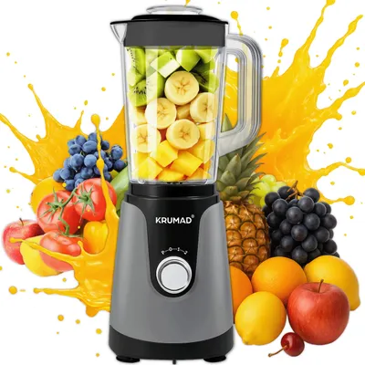 A blender filled with fruit is surrounded by various fruits and splashes of orange juice, suggesting a smoothie-making context.