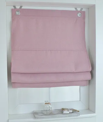 A pink Roman blind is shown hanging in a window frame, with decorative items on the windowsill below.