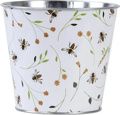 A white metal pot with a pattern of bees and flowers.