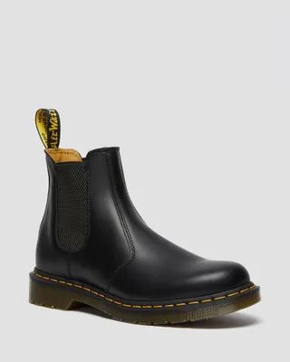 A black Dr. Martens Chelsea boot is shown against a white background.