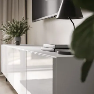 A close-up shot of a white TV cabinet with books and a lamp on top, in a modern interior setting.