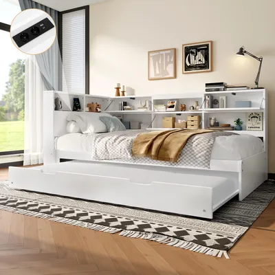 A white daybed with a pull-out trundle bed, set up in a bedroom with a window and decorative items on the shelves.