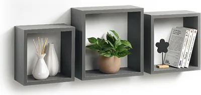 Three grey cube-shaped wall shelves mounted on a white wall, each displaying decorative items.