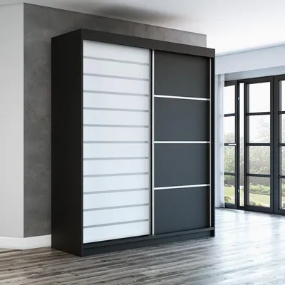 A modern sliding door wardrobe in a room with a concrete wall and large windows.