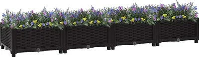 A long, black, rectangular planter box filled with purple and yellow flowers, set against a white background.