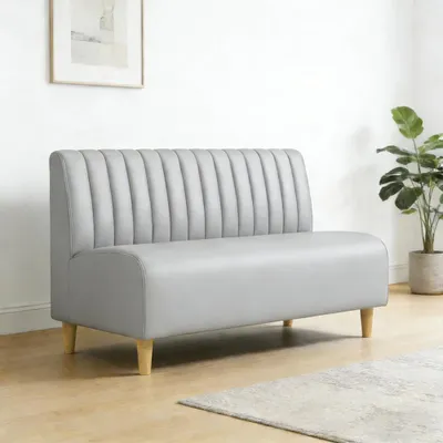 A grey sofa in a room with a plant and a picture on the wall.