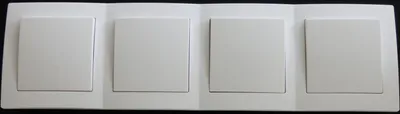 A row of four white light switches on a white plate.