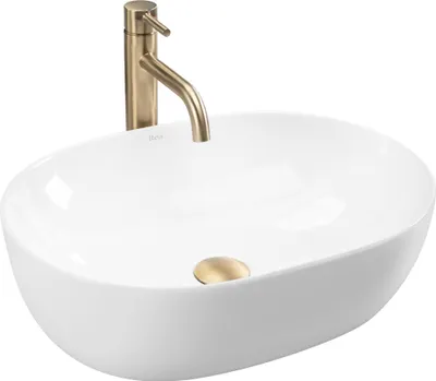 A white oval countertop sink with a gold faucet and drain.